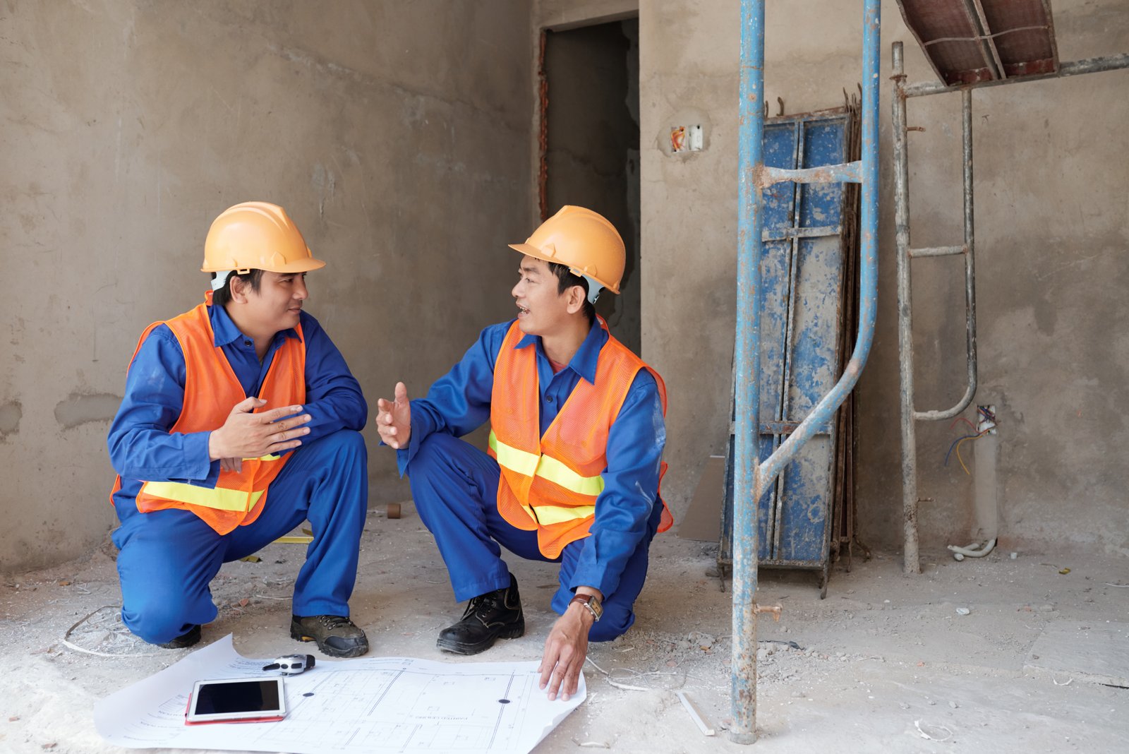 Cheerful Vietnamese construction workers discussing project of building